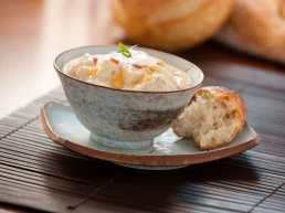 A headshot of a bowl of soup with bread on top.