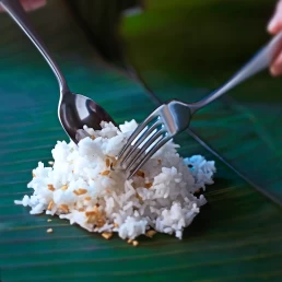 Two forks with rice on a banana leaf, captured in an exquisite food photography style.
