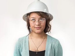 A young woman wearing a hard hat and glasses for her company headshot.