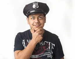 A young man in a police uniform posing for a company headshot with his hand on his chin.