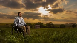 A man in a wheelchair in a field for healthcare photography.