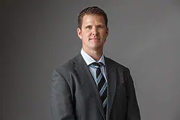 A man in a suit and tie posing for a company headshot photo.