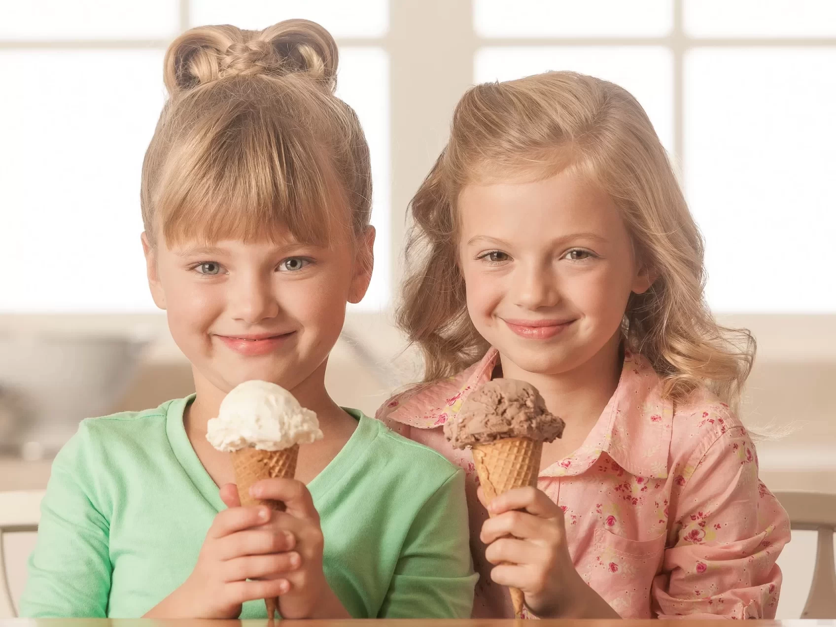 Two girls holding ice cream cones in front of a table, captured in a professional food photography style.