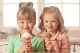 Two girls holding ice cream cones in front of a table, captured in a professional food photography style.