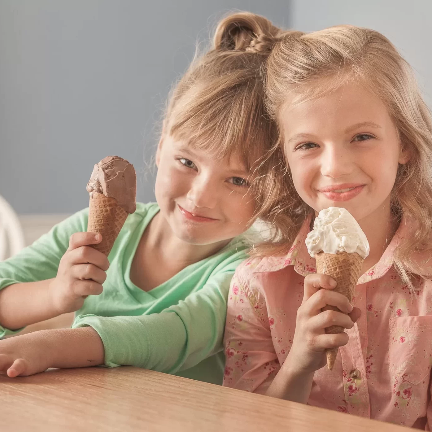 Two girls holding ice cream cones at a table for a company headshot.