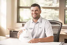 A man sitting at a desk holding a hard hat for a healthcare photography shoot.