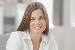 A woman sitting at a desk with a smile on her face for a healthcare photography session.
