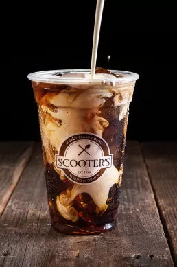 An iced coffee is being poured into a cup for a company headshot.