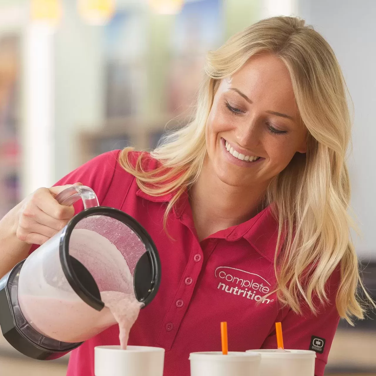 A woman pouring milk into a cup for food photography.