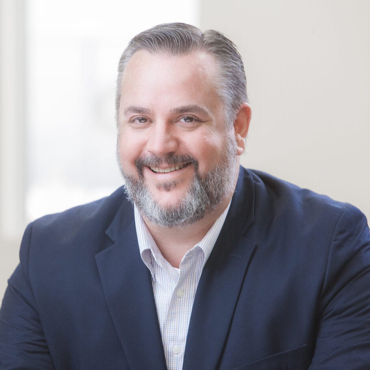 A smiling man in a suit sitting at a desk for a healthcare photography.