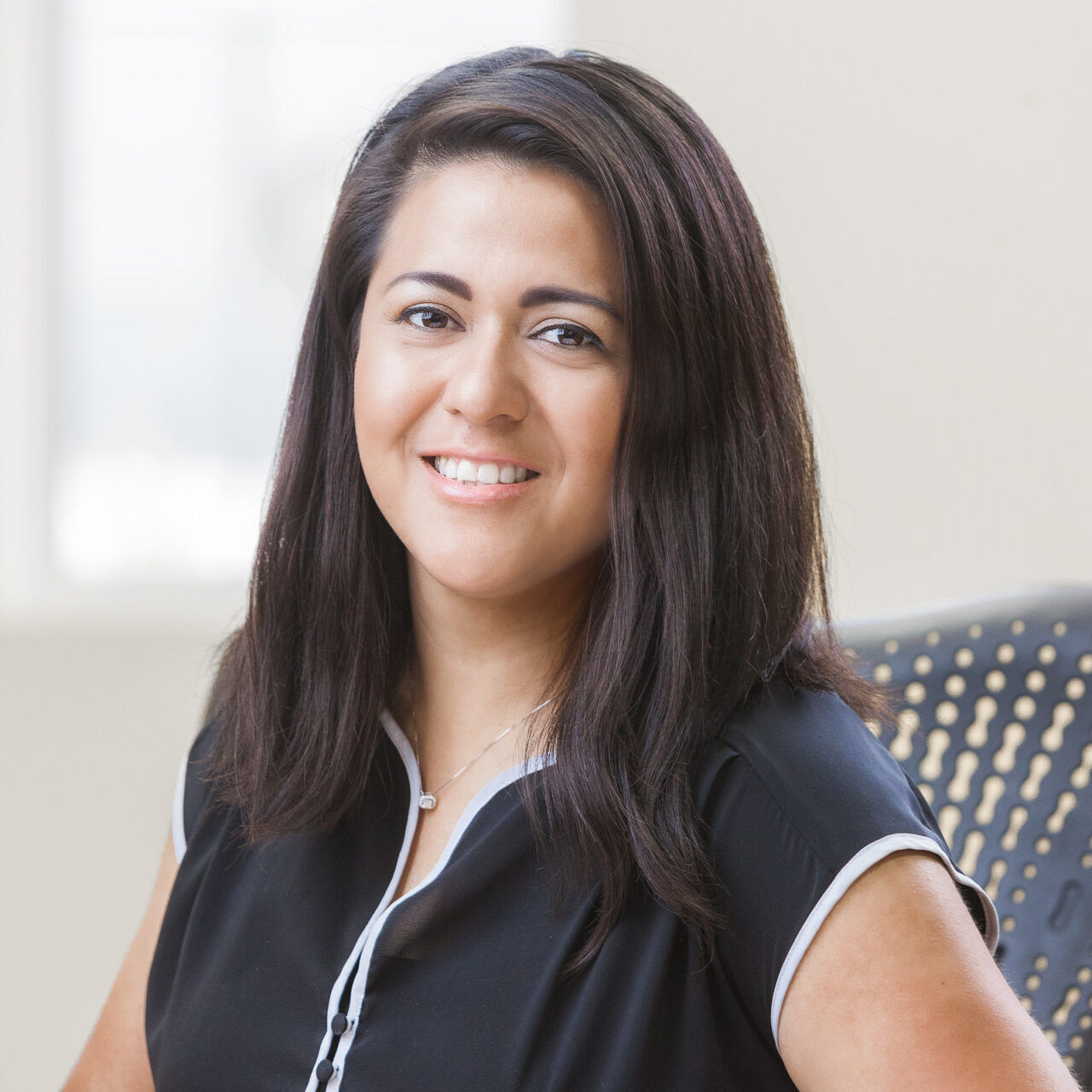 A woman in a black shirt sitting at a desk for her company headshot.