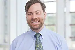 A company Headshot of a man smiling at the camera.