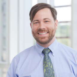 A company Headshot of a man smiling at the camera.