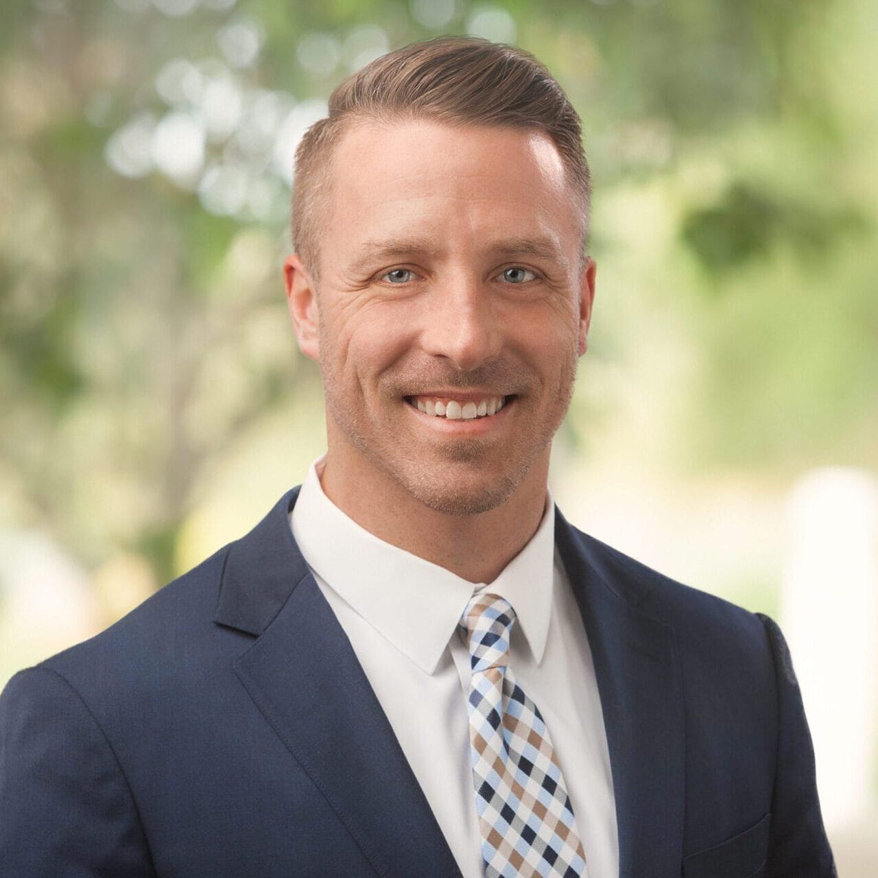 A man in a suit smiles for the camera for his company headshot.