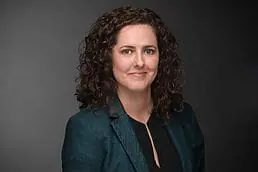 A woman with curly hair is posing for a headshot photo.