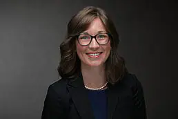 A woman in glasses is smiling for the camera in her company headshot.