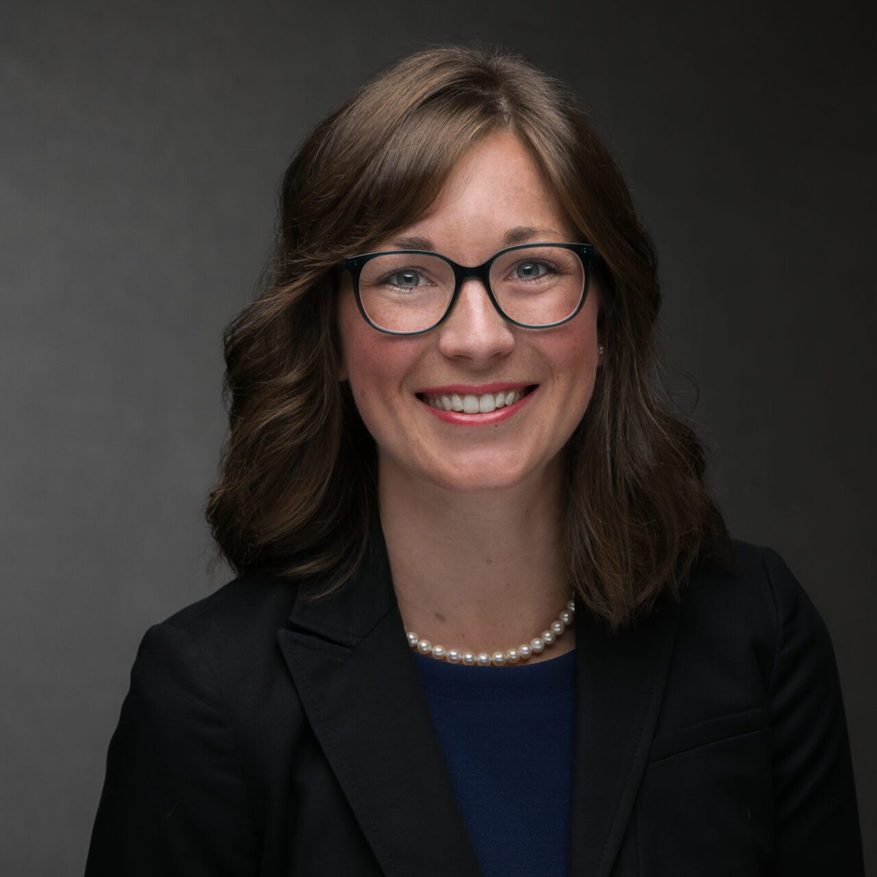 A woman in glasses is smiling for the camera in her company headshot.