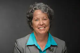 A woman in a gray shirt smiling for the headshot.