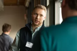 A man is talking to another man in a conference room about business