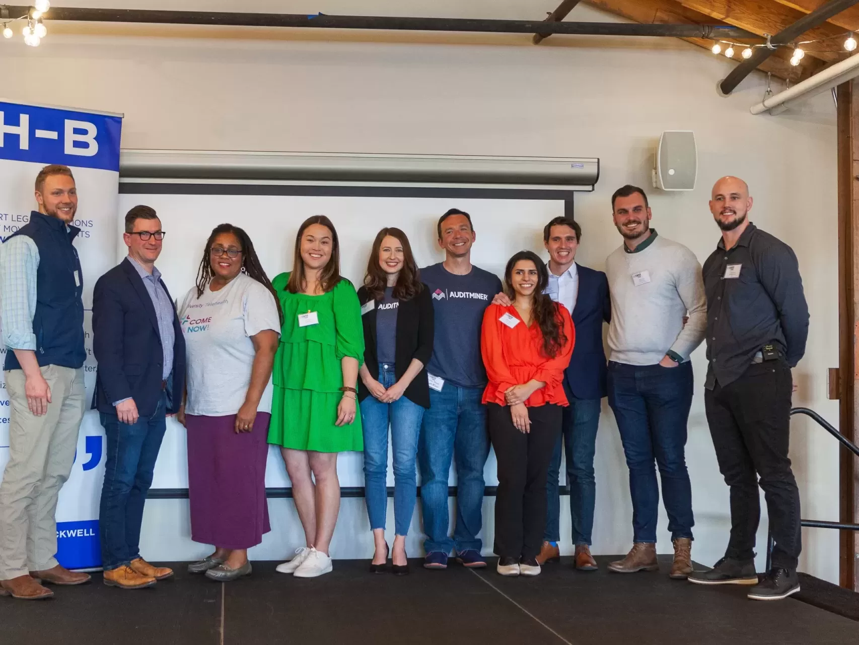 A group of people posing for a group photo in front of a screen.