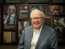 Warren Buffett in front of a wall of photos.