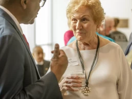 An older woman talking to a man at an event about healthcare photography.