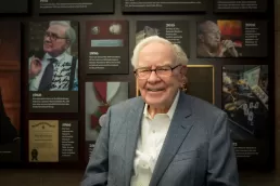 Warren Buffett in front of a wall of photos.