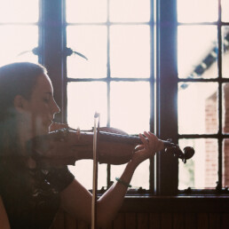 A woman playing a violin in front of a window at a corporate event.