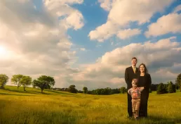 A family is posing in a field under a cloudy sky for a healthcare photography session.