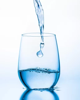 Water being poured into a glass, captured in a healthcare photography setting.