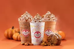 Three coffee drinks with pumpkins and whipped cream, captured in a stunning food photography setting.