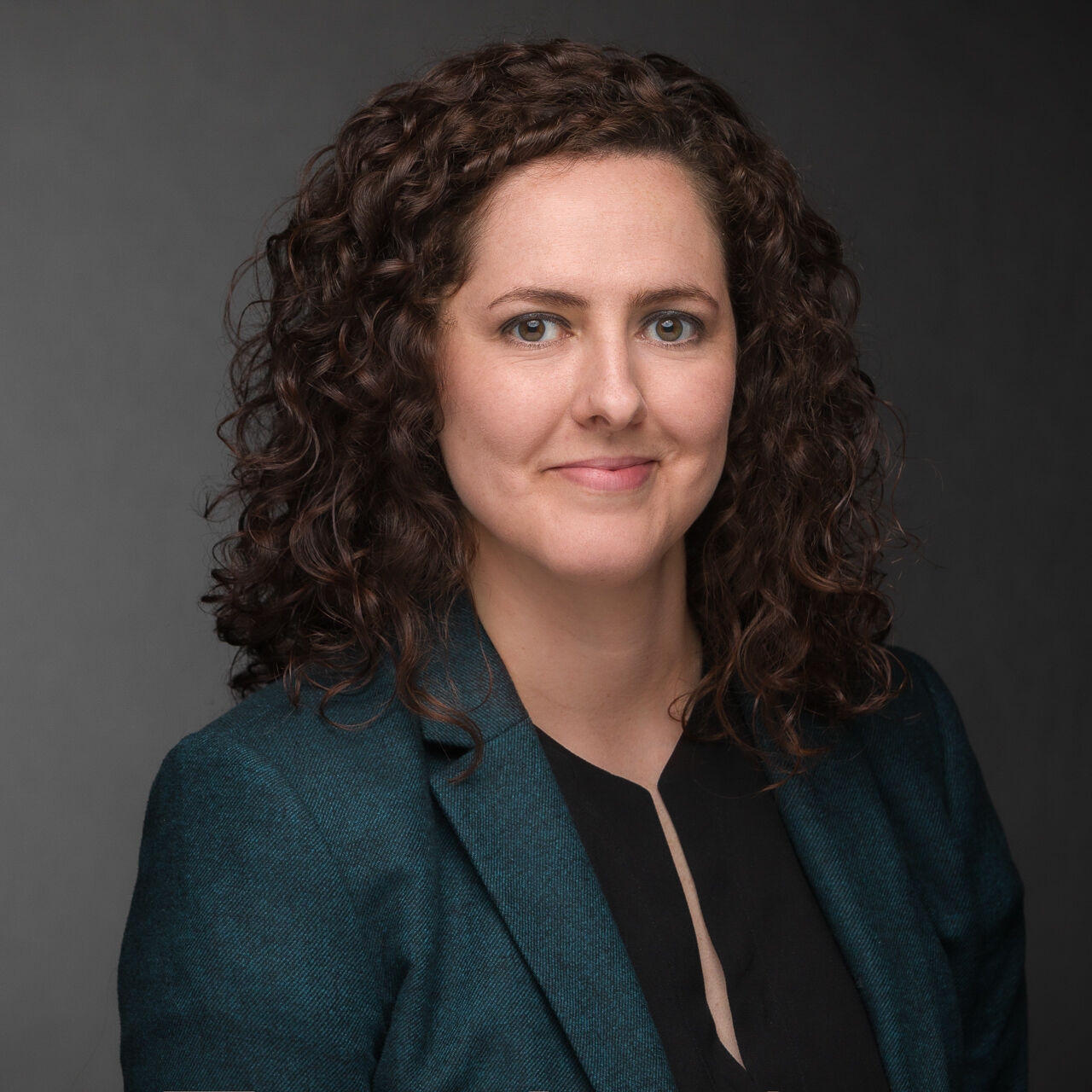 A woman with curly hair is posing for a headshot photo.