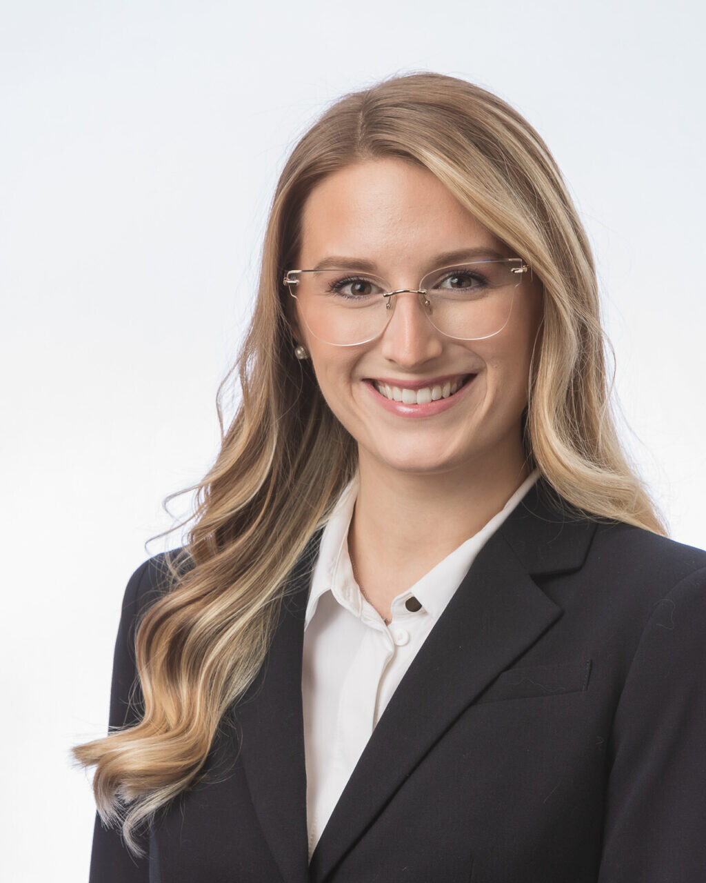 A young woman in a business suit smiling for a headshot.