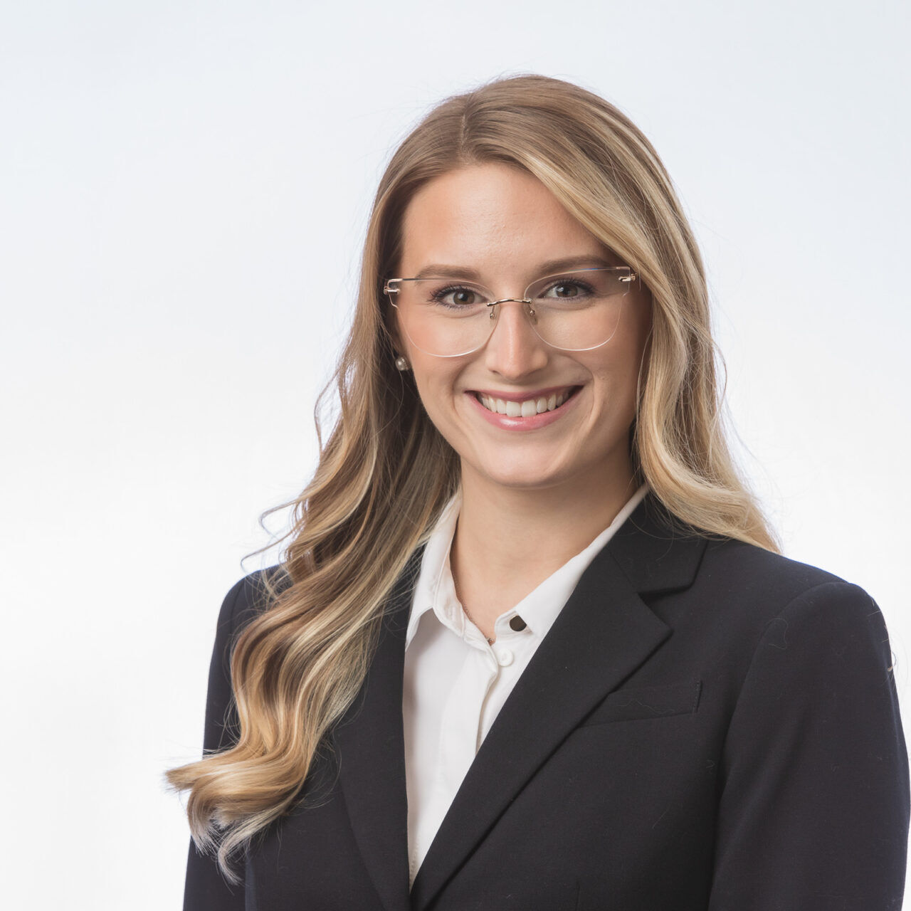 A young woman in a business suit smiling for a headshot.