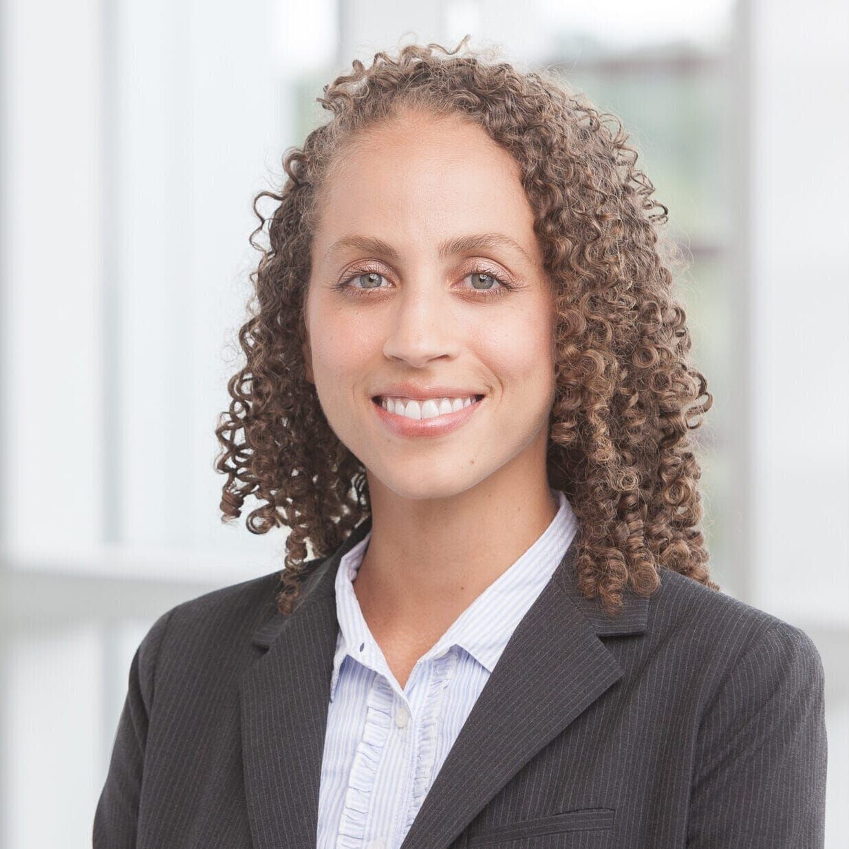 A woman with curly hair wearing a suit in her headshot.