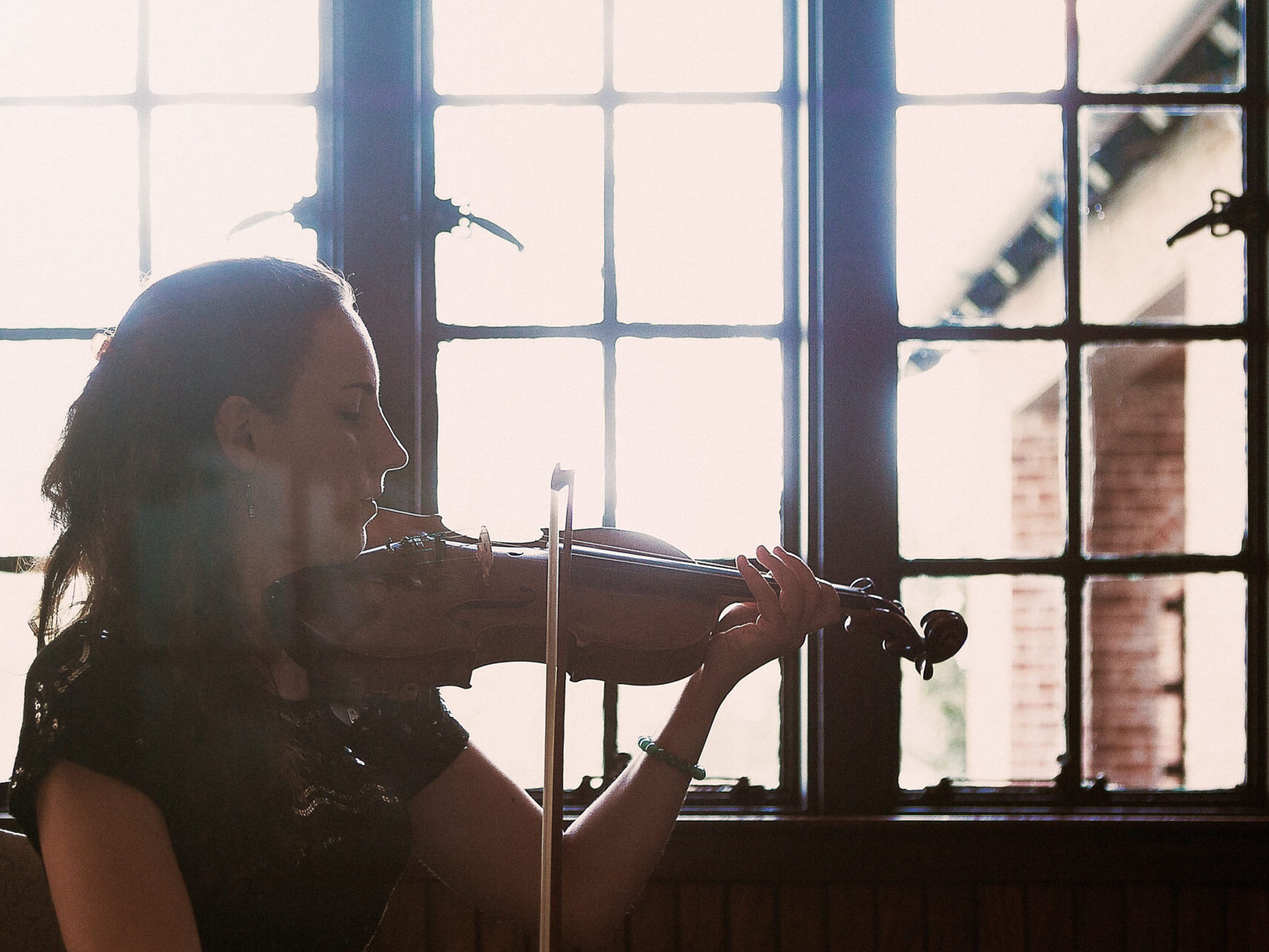 A woman playing a violin in front of a window at a corporate event.