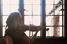 A woman playing a violin in front of a window at a corporate event.