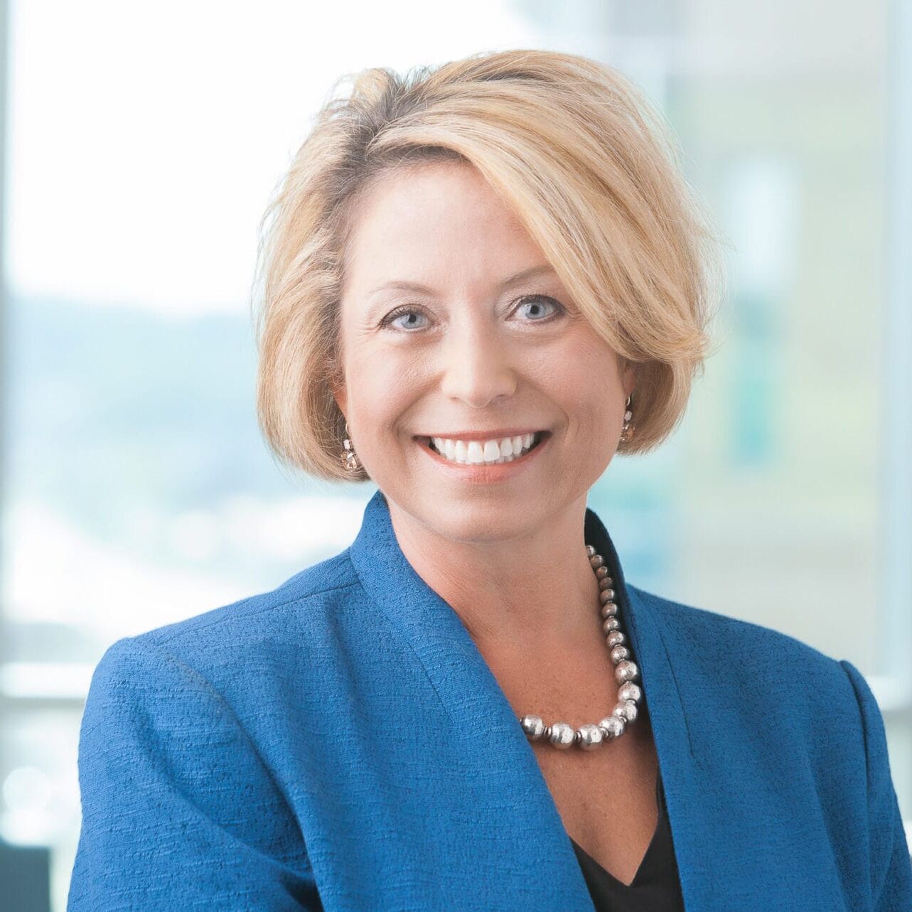 A smiling woman in a blue suit poses for her company headshot.