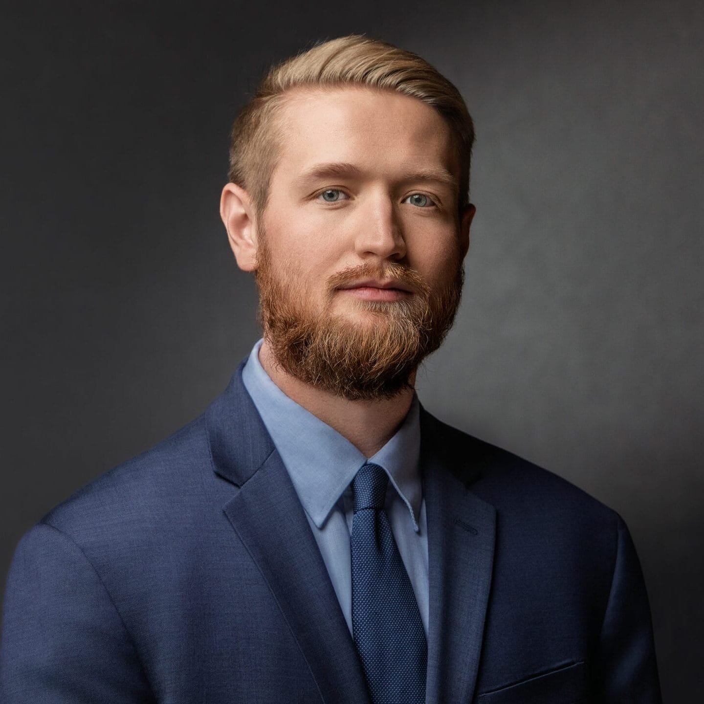 Professional headshot of Brooks Mason in a navy suit with a composed expression.