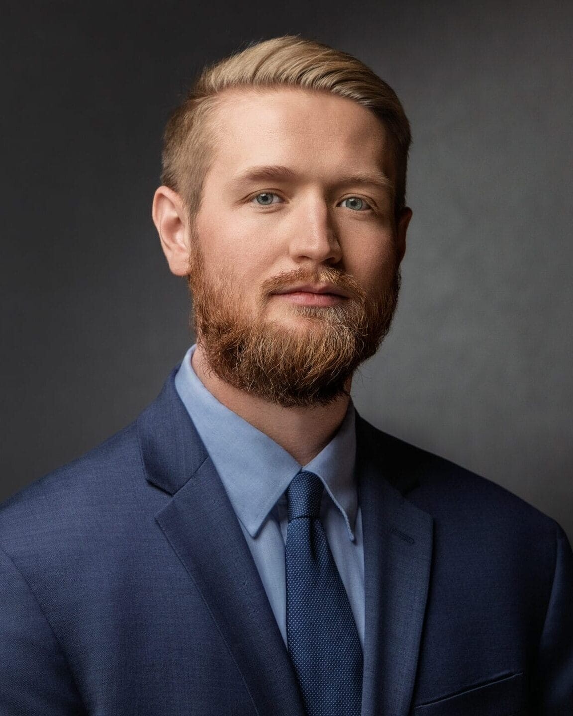 Professional headshot of Brooks Mason in a navy suit with a composed expression.