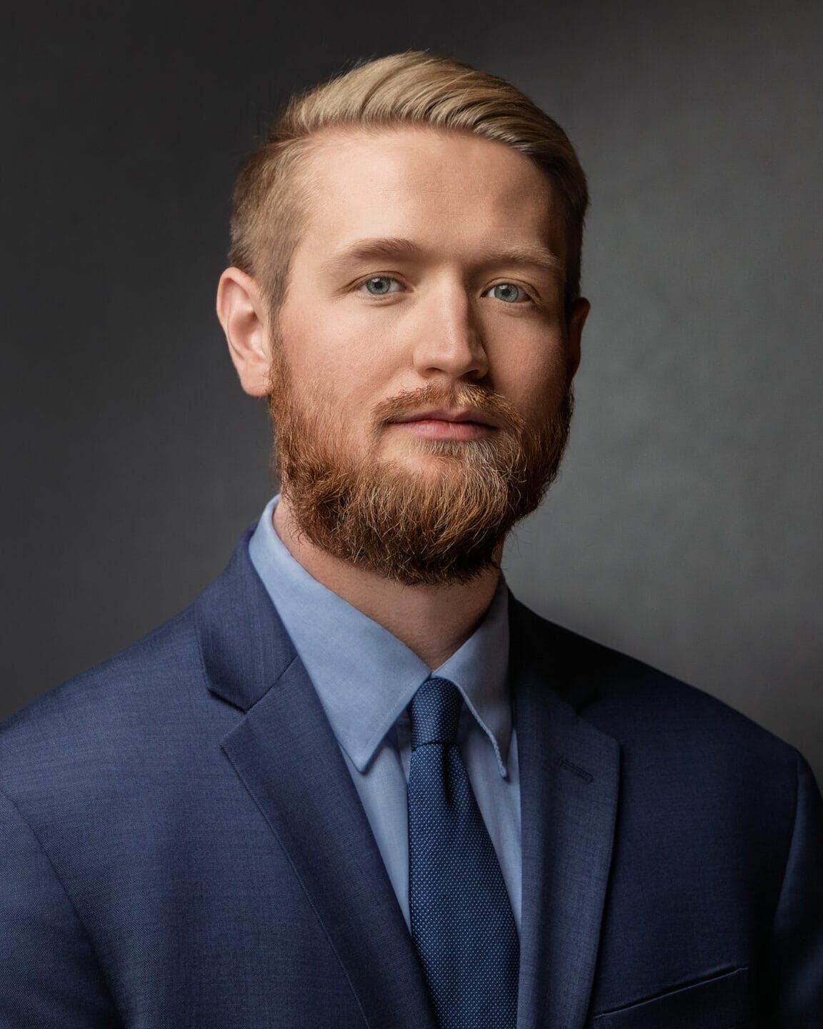 Professional headshot of Brooks Mason in a navy suit with a composed expression.